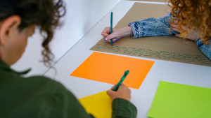 2 people writing with colored markers on craft paper