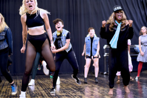 People in workout wear and street clothes (denim jackets) engaged in exercise class