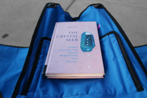 book The Crystal Seer on armrest of blue camp chair