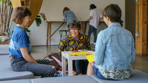 3 folks sitting around table, talking